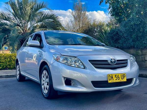 Used Toyota Corolla for sale - Model shown is a light blue 2010 Automatic Corolla in great condition with low KMS - Photo showing the front driver passenger side angle view shot from a low angle