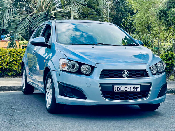 Used Holden Barina for sale in Sydney - Metallic light blue 2012 model with low kms - photo showing the front straight on view with colour matching front bumper and grille